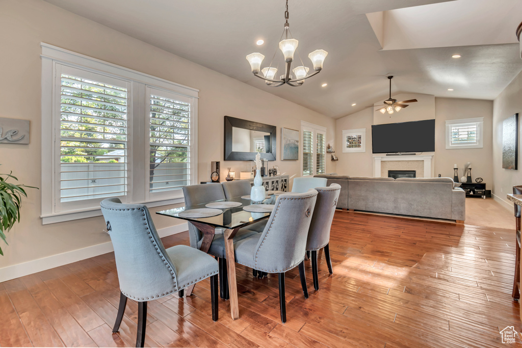 Dining area with ceiling fan with notable chandelier, vaulted ceiling, and hardwood / wood-style floors