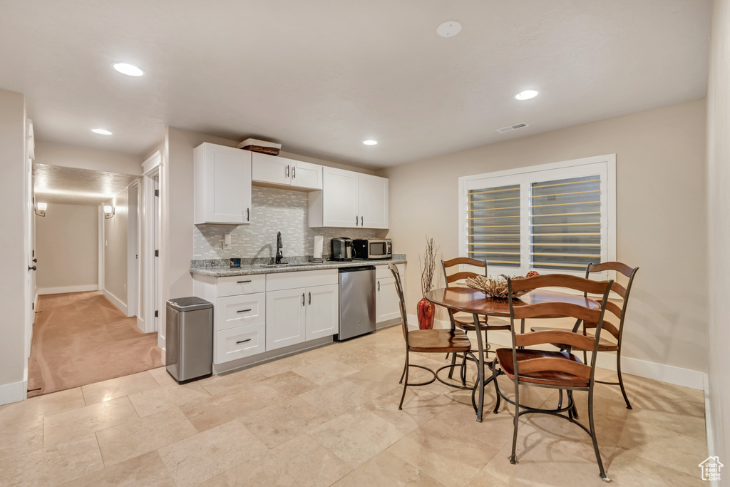 Kitchen featuring backsplash, appliances with stainless steel finishes, white cabinetry, and light tile floors