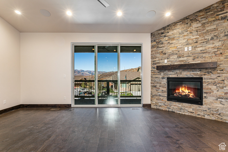 Unfurnished living room featuring dark hardwood / wood-style flooring, a fireplace, and vaulted ceiling