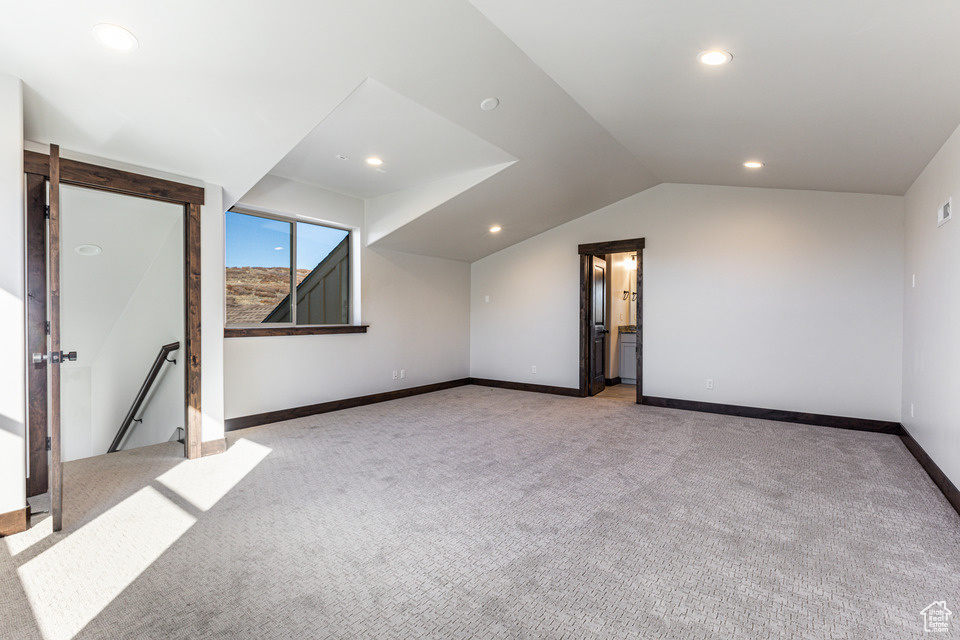 Bonus room with light colored carpet and lofted ceiling