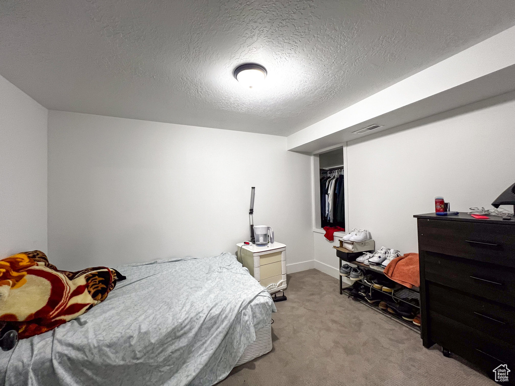 Carpeted bedroom featuring a closet and a textured ceiling