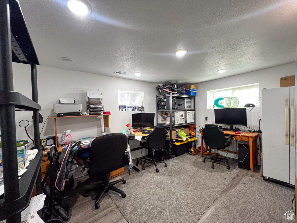 Carpeted home office featuring a textured ceiling