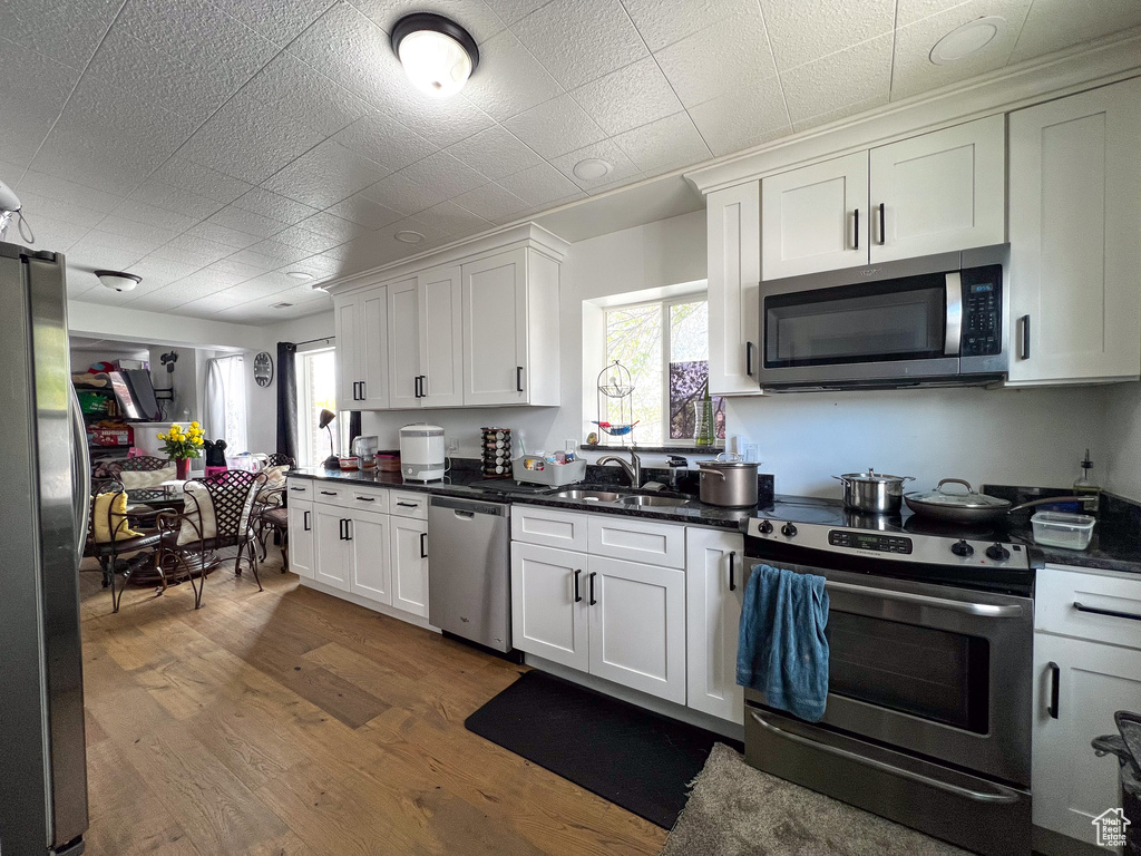 Kitchen featuring appliances with stainless steel finishes, sink, hardwood / wood-style flooring, and white cabinetry