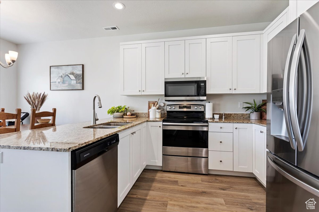 Kitchen featuring white cabinets, appliances with stainless steel finishes, sink, and light hardwood / wood-style floors