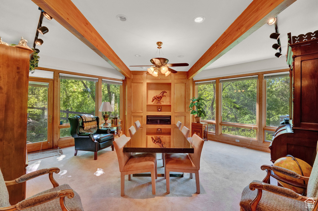 Dining room featuring a healthy amount of sunlight, beamed ceiling, and light carpet