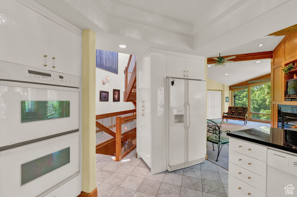 Kitchen featuring vaulted ceiling, light tile flooring, ceiling fan, white cabinets, and white appliances