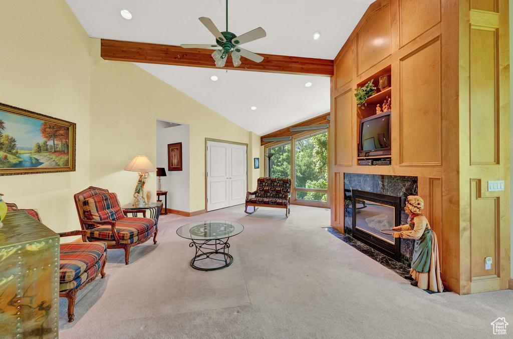 Living room with a high end fireplace, ceiling fan, beamed ceiling, light colored carpet, and high vaulted ceiling