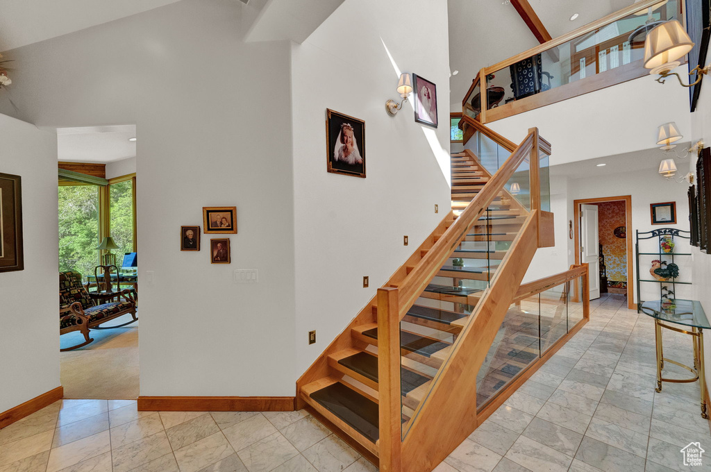 Stairway featuring high vaulted ceiling and light tile flooring