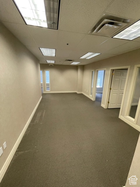 Empty room featuring dark colored carpet and a paneled ceiling