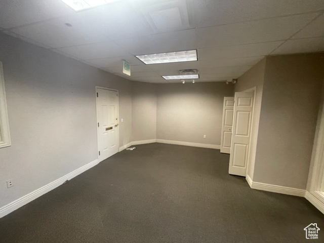 Spare room with dark colored carpet and a paneled ceiling