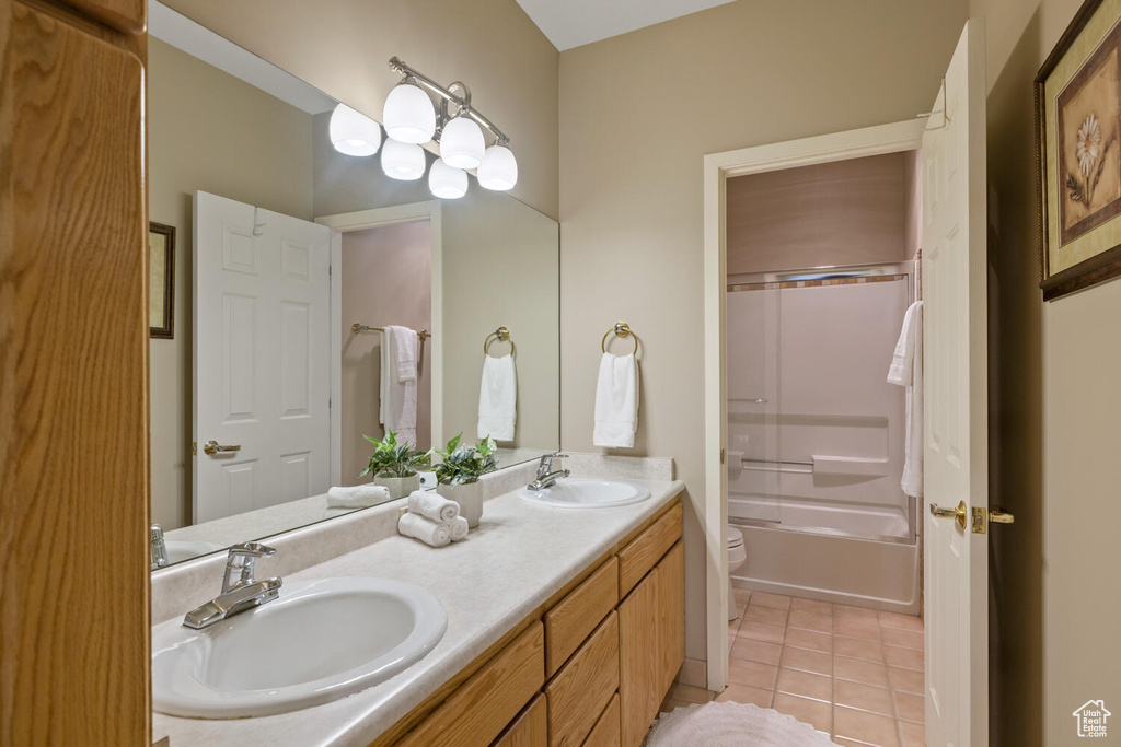 Full bathroom with tile flooring, shower / tub combination, large vanity, toilet, and dual sinks