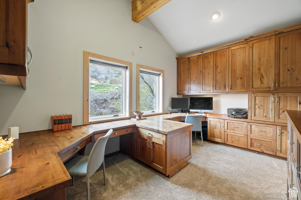 Office with light colored carpet, beamed ceiling, built in desk, and high vaulted ceiling