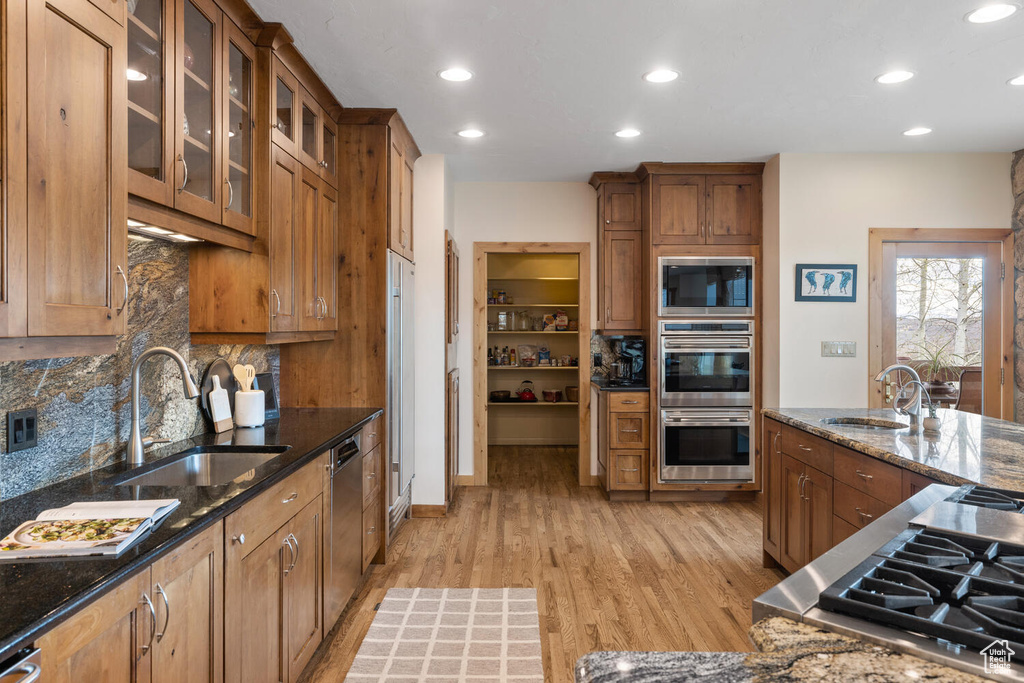 Kitchen with backsplash, dark stone countertops, appliances with stainless steel finishes, and sink