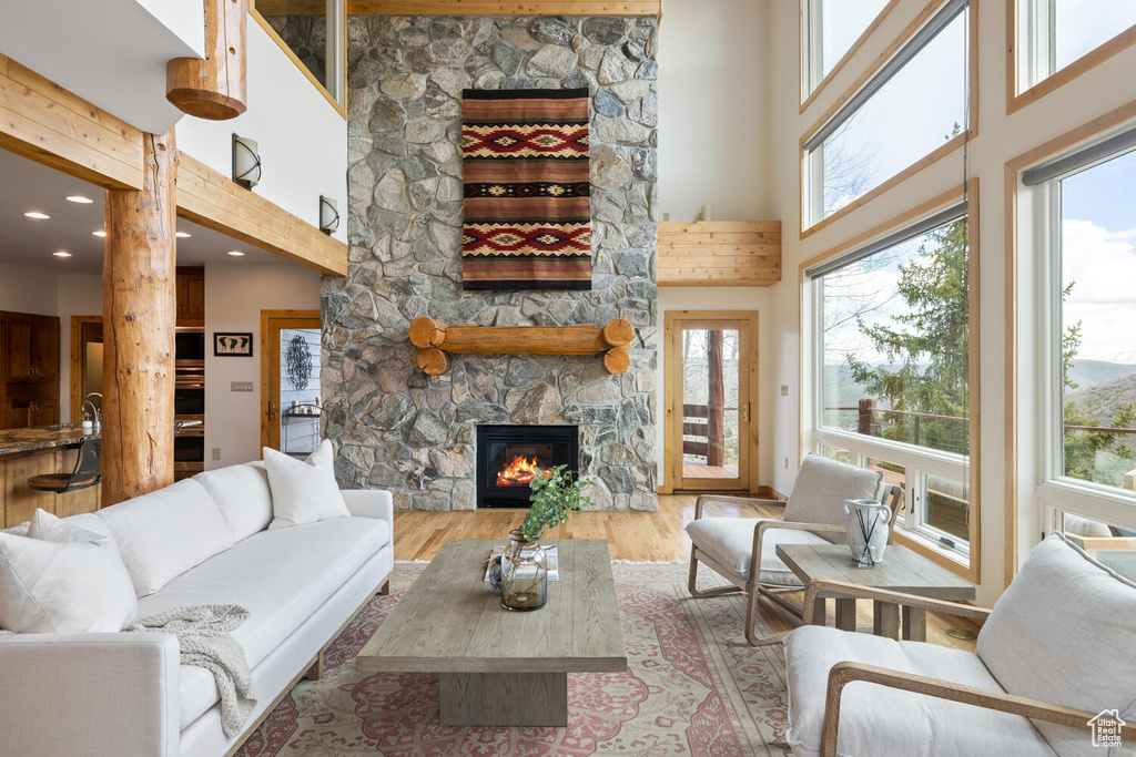 Living room with a stone fireplace, a high ceiling, and hardwood / wood-style flooring