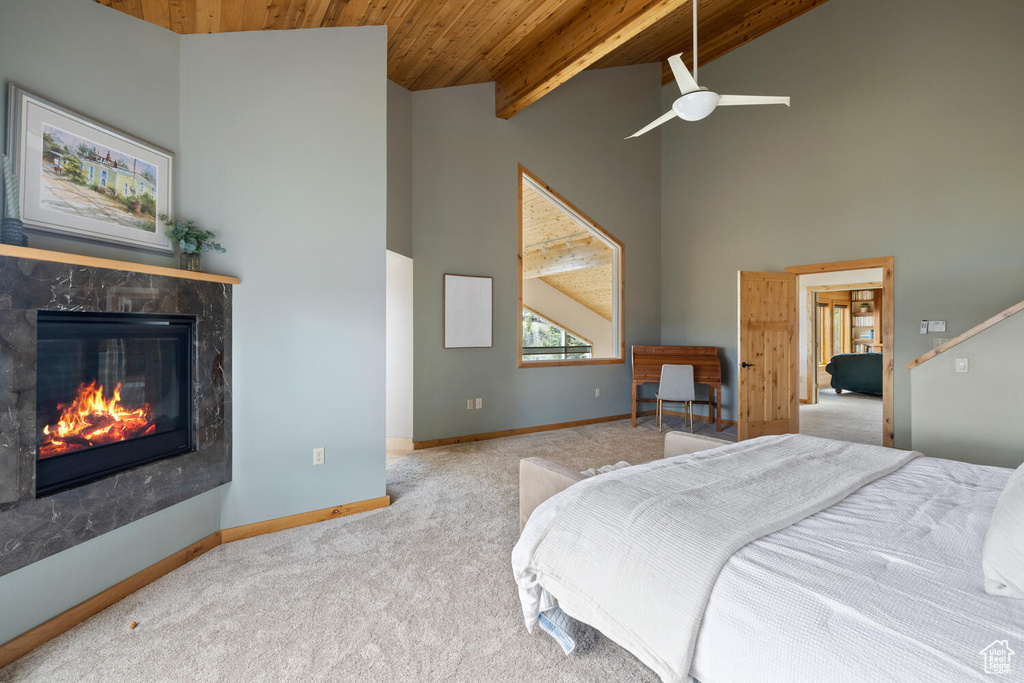 Carpeted bedroom featuring ceiling fan, beamed ceiling, a premium fireplace, high vaulted ceiling, and wooden ceiling