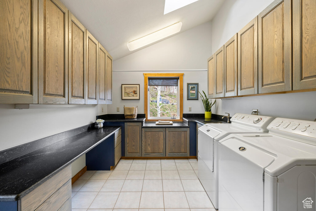 Laundry room with light tile floors, sink, washer and clothes dryer, a skylight, and cabinets