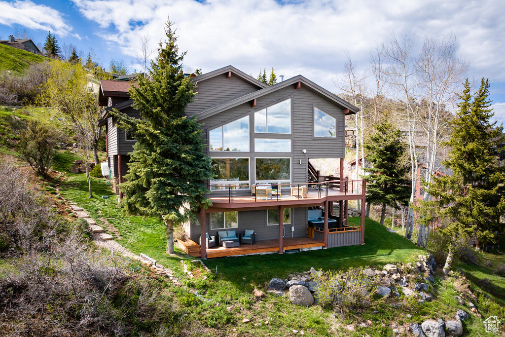 Rear view of property featuring a deck and a yard