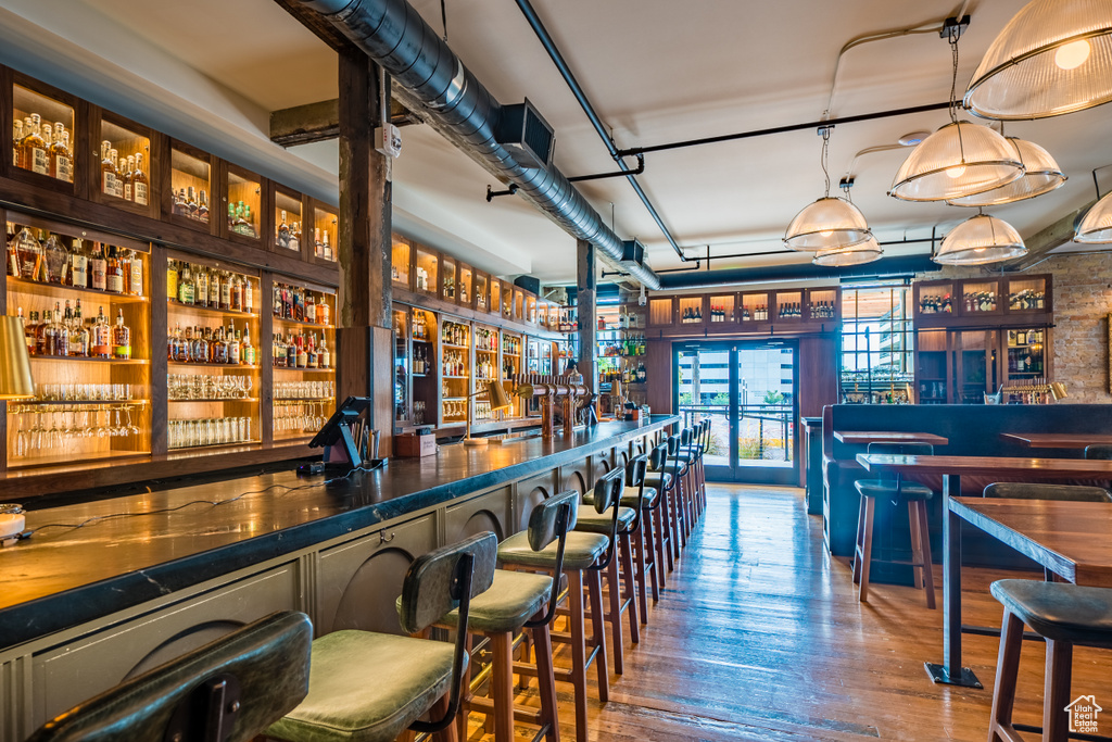 Bar featuring wood-type flooring and hanging light fixtures