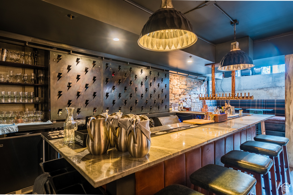 Bar featuring stone countertops and pendant lighting