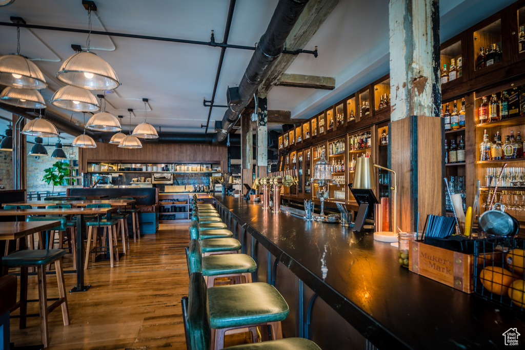 Bar featuring hanging light fixtures and hardwood / wood-style flooring