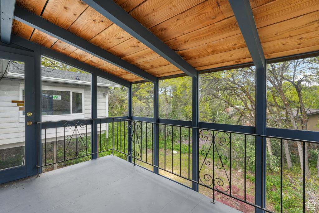 Unfurnished sunroom with vaulted ceiling with beams and wooden ceiling