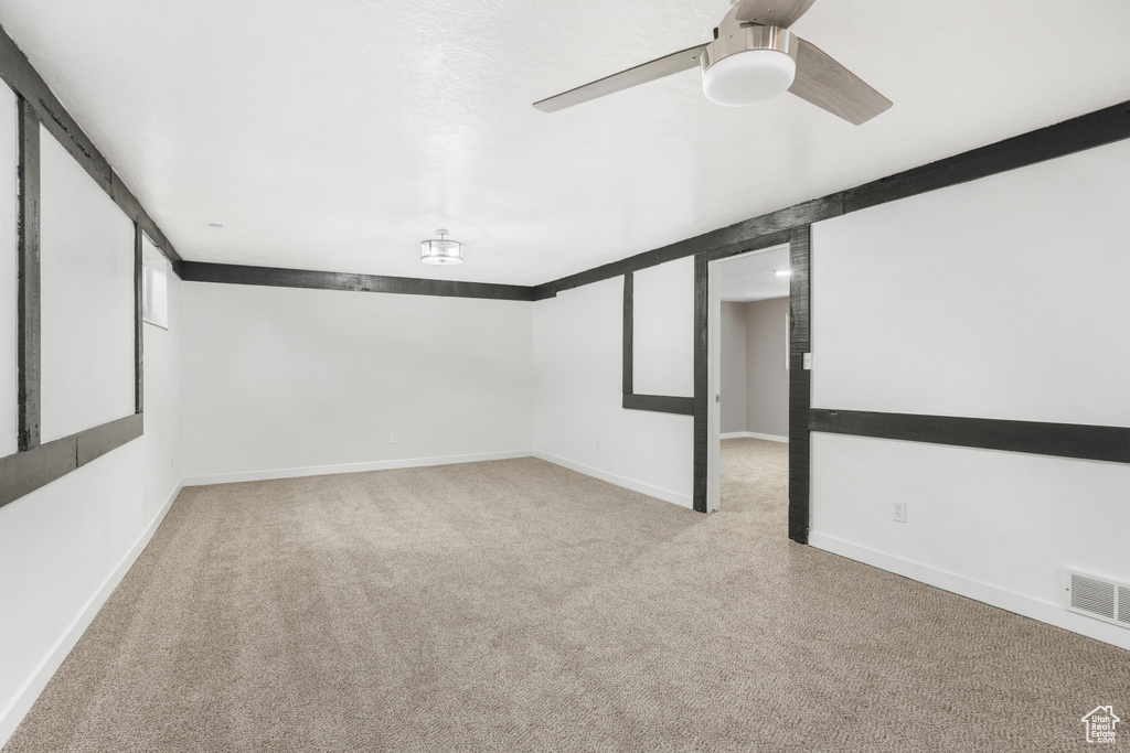 Basement featuring light carpet and ceiling fan