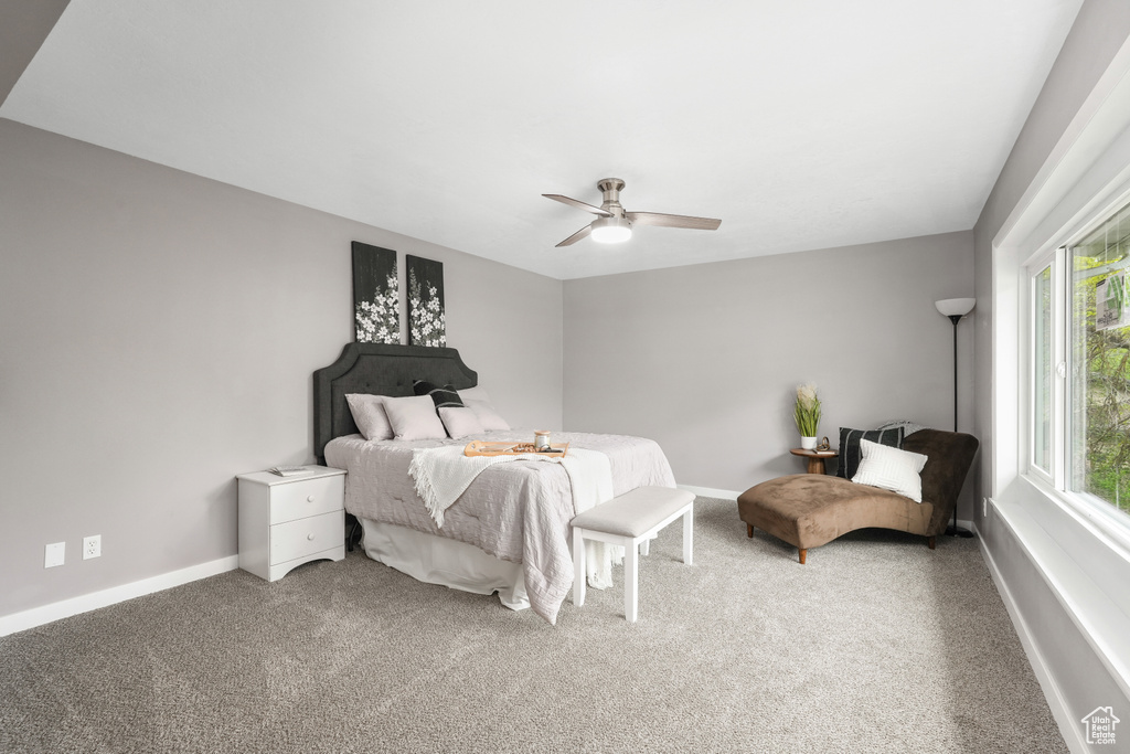 Carpeted bedroom with ceiling fan and multiple windows