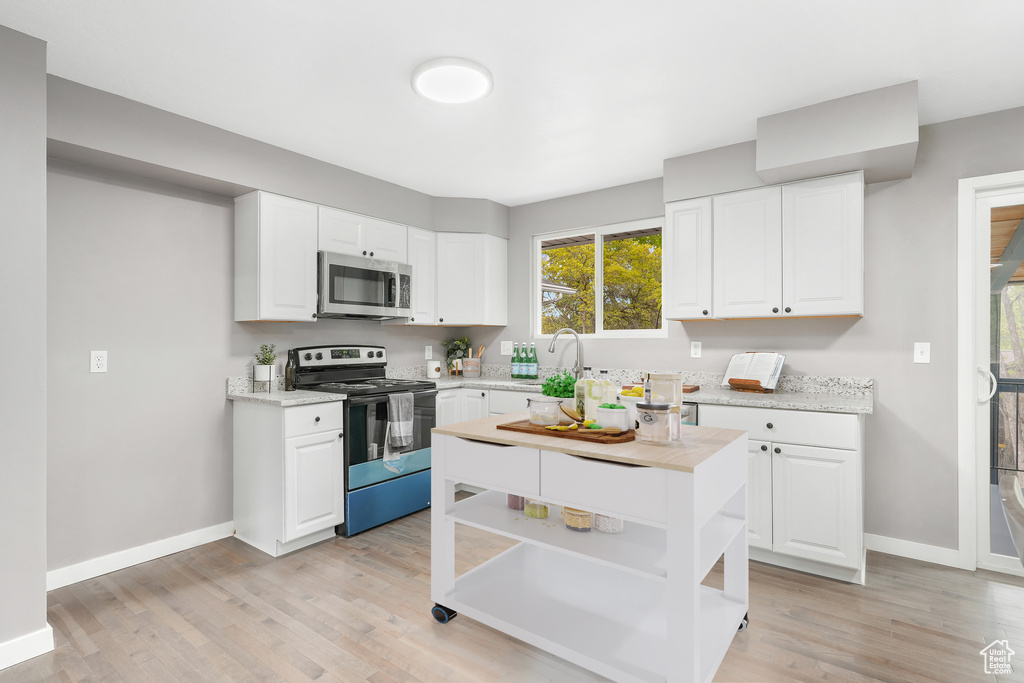 Kitchen featuring light hardwood / wood-style floors, white cabinetry, and appliances with stainless steel finishes