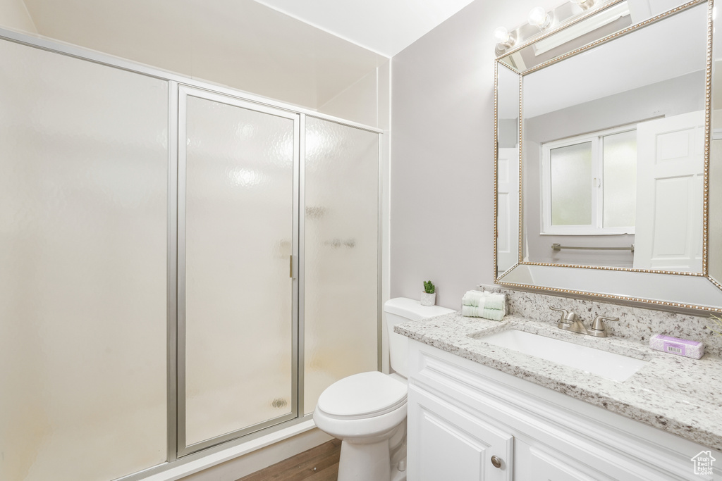 Bathroom with wood-type flooring, an enclosed shower, vanity, and toilet