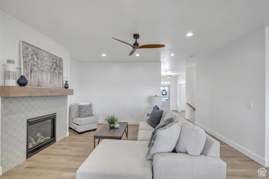 Living room featuring ceiling fan, light hardwood / wood-style floors, and a fireplace