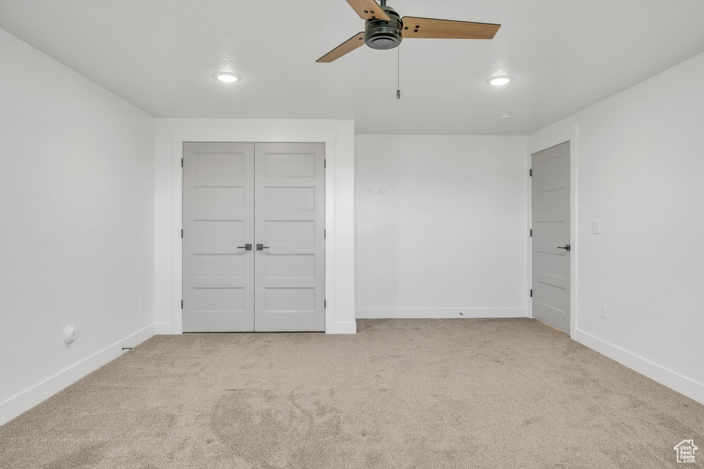 Unfurnished bedroom featuring light carpet, a closet, and ceiling fan