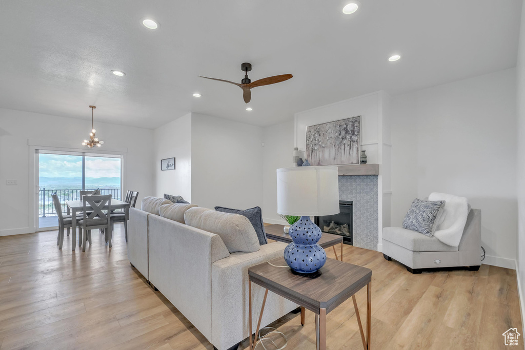 Living room with light hardwood / wood-style floors and ceiling fan with notable chandelier