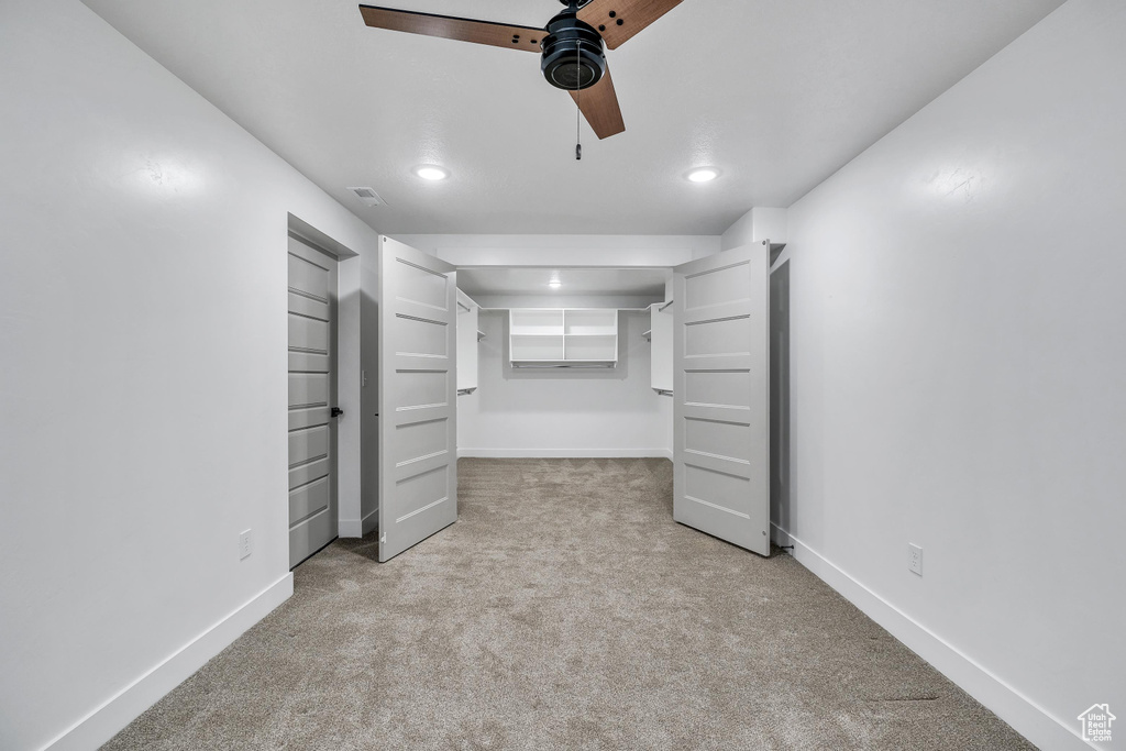 Unfurnished bedroom with light colored carpet and ceiling fan