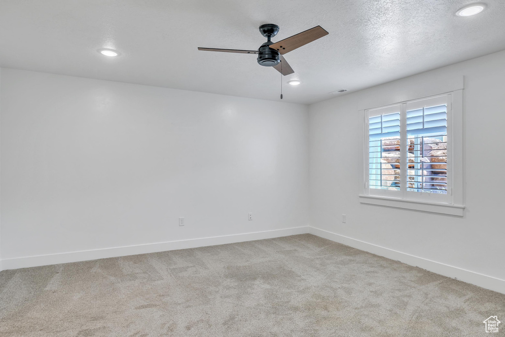 Carpeted empty room with ceiling fan and a textured ceiling