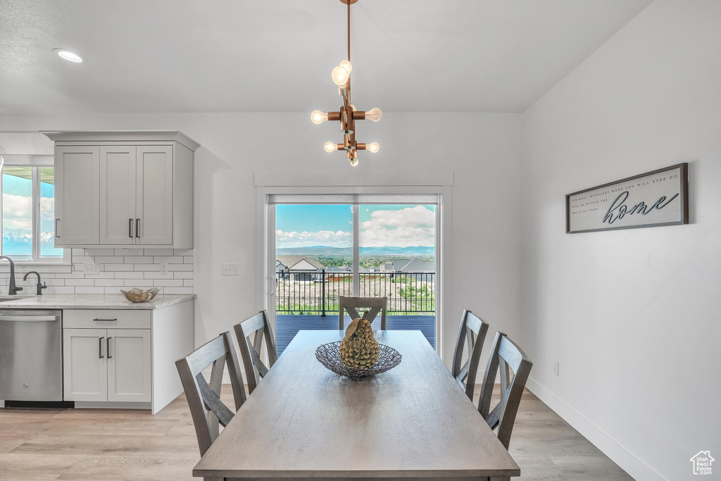 Dining area with a notable chandelier, sink, light hardwood / wood-style floors, and a wealth of natural light