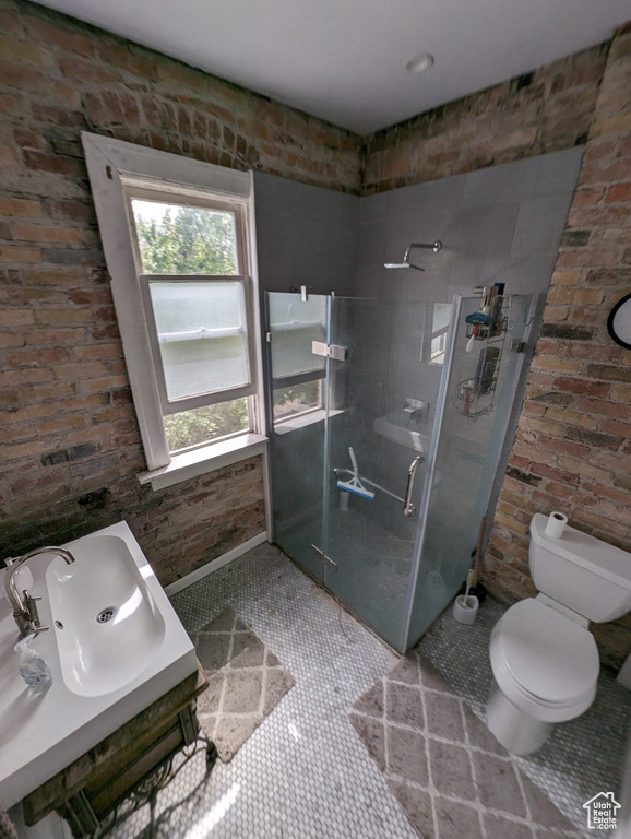 Bathroom with tile floors, walk in shower, toilet, and brick wall