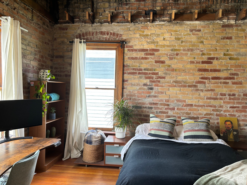 Bedroom with hardwood / wood-style flooring and brick wall