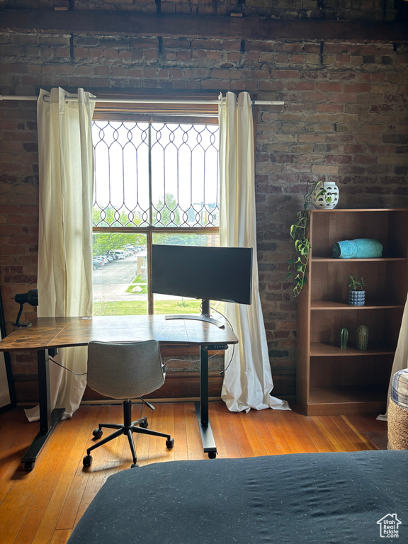 Office with brick wall and wood-type flooring