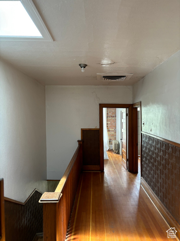 Hallway featuring hardwood / wood-style flooring and radiator heating unit