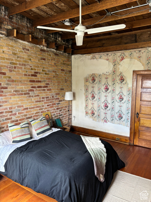 Bedroom with beamed ceiling, wooden ceiling, dark hardwood / wood-style floors, and brick wall