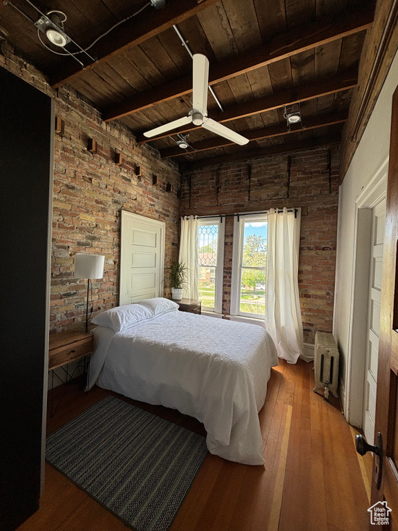 Bedroom with beam ceiling, wood ceiling, radiator, and hardwood / wood-style floors