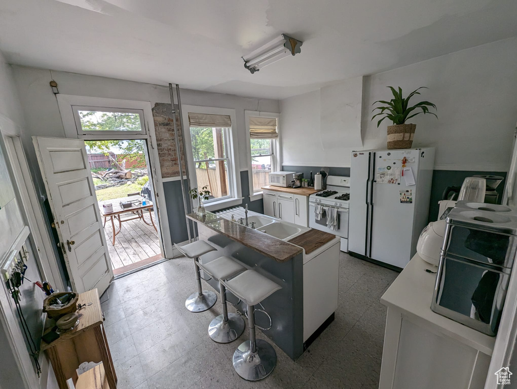 Kitchen with sink, white cabinetry, white appliances, and tile floors