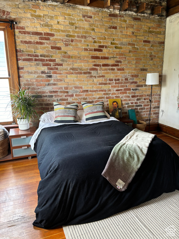 Bedroom featuring brick wall and hardwood / wood-style floors