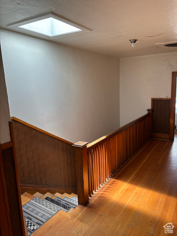 Stairs featuring hardwood / wood-style floors and a skylight