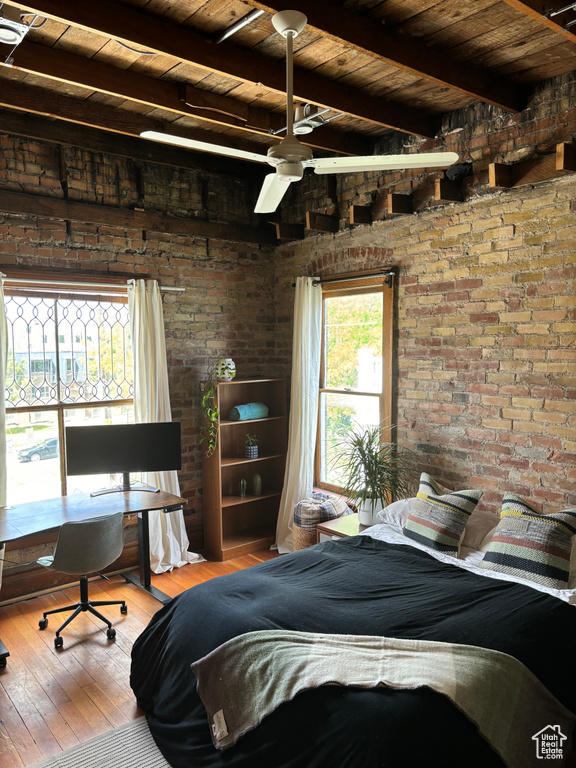 Bedroom featuring beam ceiling, hardwood / wood-style flooring, wood ceiling, and brick wall