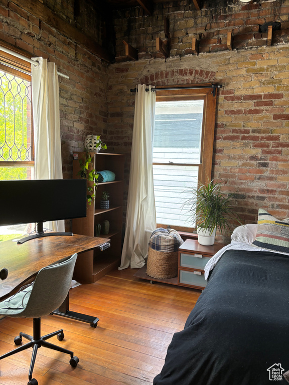 Bedroom with brick wall and wood-type flooring