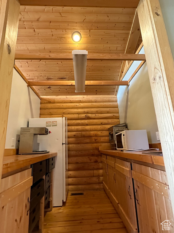 Kitchen featuring light hardwood / wood-style floors, rustic walls, and lofted ceiling