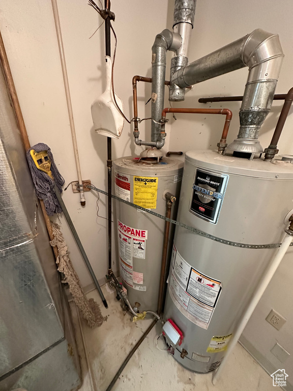 Utility room featuring secured water heater and gas water heater