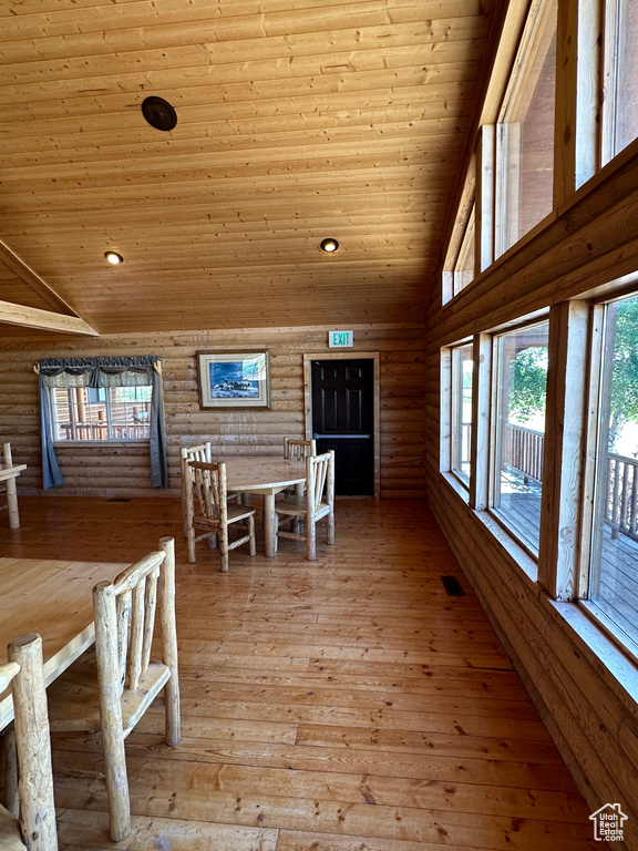 Unfurnished dining area featuring high vaulted ceiling, wooden ceiling, light hardwood / wood-style floors, and log walls