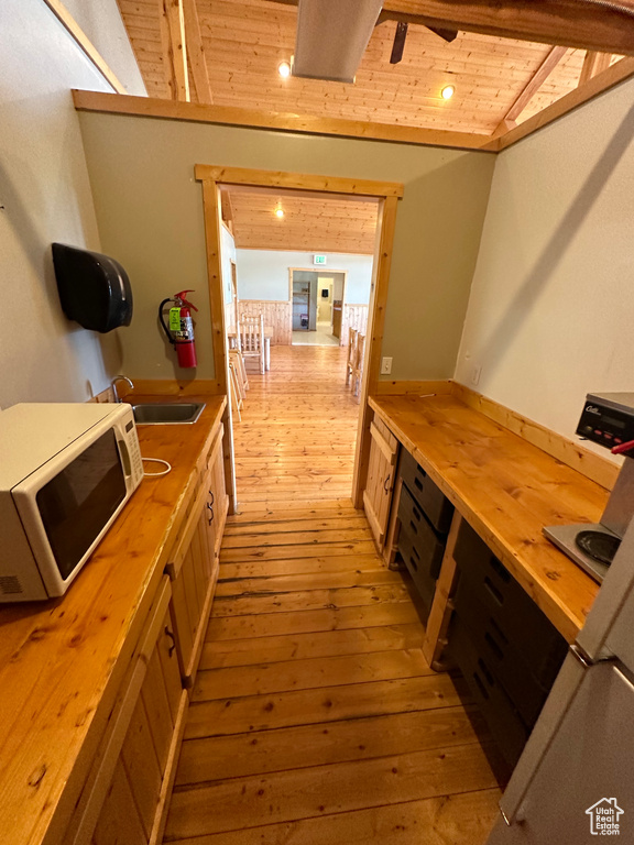 Kitchen with vaulted ceiling with beams, light wood-type flooring, butcher block countertops, and wooden ceiling